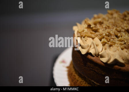 Leckere hausgemachte Kuchen mit Kaffee buttercream top und sprengte mit Muttern und einen dunklen Hintergrund Stockfoto