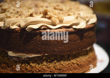 Leckere hausgemachte Kuchen mit Kaffee buttercream top und sprengte mit Muttern und einen dunklen Hintergrund Stockfoto