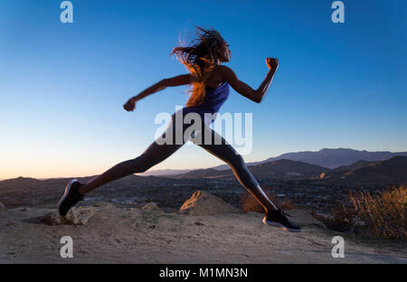 Junge afrikanische amerikanische Frau läuft auf einem Berg bei einem Sonnenuntergang in Kalifornien. Foto von Francis Specker Stockfoto