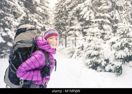 Frau wandern in weiss Winter Forest Woods mit Rucksack. Junge Mädchen zu Fuß auf verschneiten Trail. Erholung Fitness und gesunde Lebensweise, Camping im Freien Stockfoto