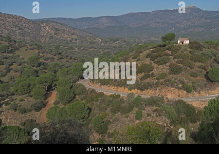 Gebirgsstrasse mit isolierten Haus auf einem Hügel mit Stone Pine Tree Parque Natural Sierra de Andujar, Jaen, Spanien Januar Stockfoto