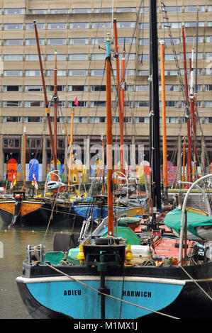 Bunte alte Thames Lastkähne in St. Catherine's Dock günstig auf der Themse in London vor einigen modernen konkrete Wohnungen oder Wohnhäusern. Stockfoto