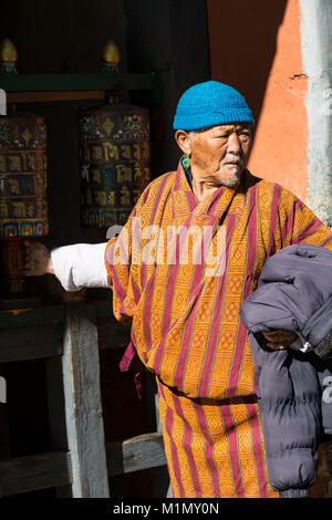 Bumthang, Bhutan. Bhutanesische Mann sich drehende Gebetsmühle am Jambay Lhakhang (Kloster/Tempel). Stockfoto