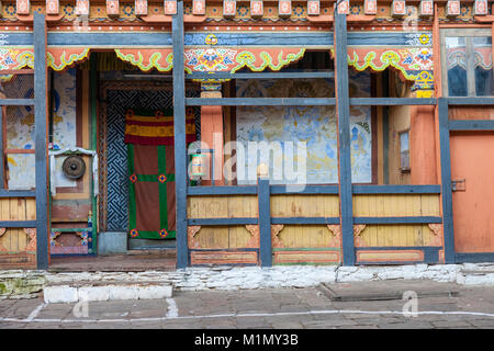 Jakar, Bumthang, Bhutan. Innenraum der Jakar Dzong. Ein Gong und eine Gebetsmühle Flanke Eingang zu einem Büro. Stockfoto