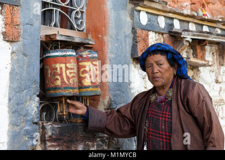 Bumthang, Bhutan. Frau Spinnen Gebetsmühlen an Jambey Lhakhang Tempel und Kloster, in der Nähe von jakar. Stockfoto
