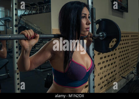 Portrait von schöne Brünette mit einem barbell in der Turnhalle. Close-up Stockfoto