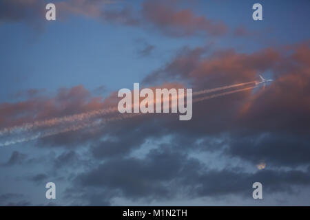 Flugzeug fliegen in der Nähe des Mondes - Rot bewölkter Sonnenuntergang Stockfoto