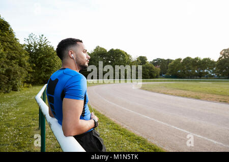 Männliche Athleten mit Kopfhörer eine Pause an einer Schiene Stockfoto