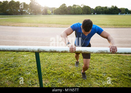 Männliche Athlet stretching an der Laufstrecke, Nahaufnahme Stockfoto