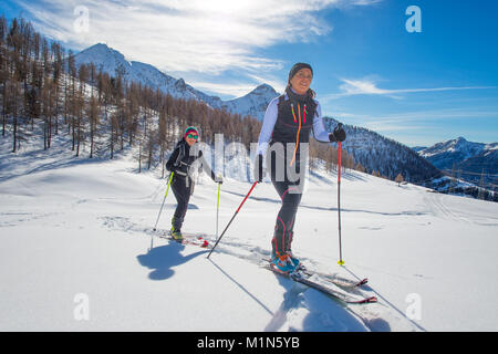 Bergauf Frauen mit Robbenfellen und Skitouren. Stockfoto