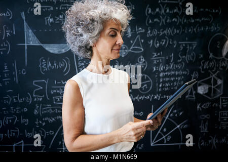 Akademische Frau mittleren Alters an der Tafel arbeiten Stockfoto