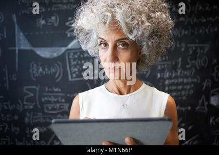 Akademische Frau mittleren Alters mit Tablet-PC auf die Kamera Stockfoto