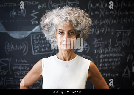 Im mittleren Alter akademischen Frau stand vor der Tafel Stockfoto