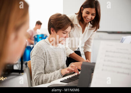 Männliche Schüler mit Lehrer spielen Klavier in der Musik Lektion Stockfoto