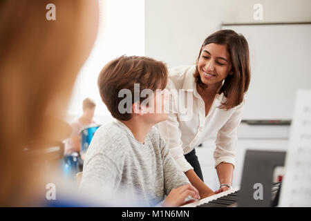 Männliche Schüler mit Lehrer spielen Klavier in der Musik Lektion Stockfoto