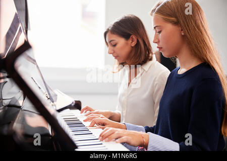 Weibliche Schüler mit Lehrer spielen Klavier in der Musik Lektion Stockfoto