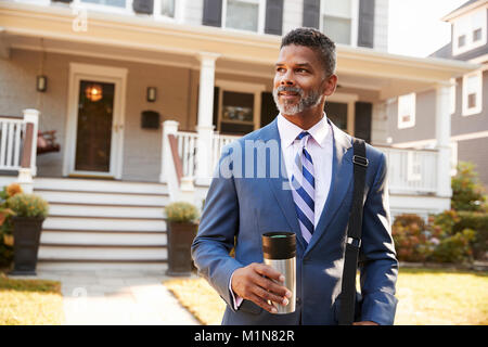 Geschäftsmann mit Tasse Kaffee verlassen Suburban House für die Arbeit Stockfoto