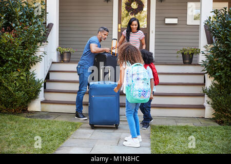 Familie mit Gepäck verlassen Haus für Ferienhäuser Stockfoto