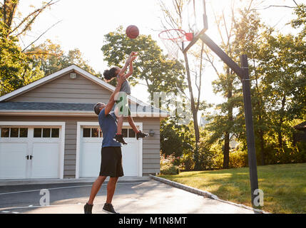 Vater und Sohn Basketball spielen in der Einfahrt zu Hause Stockfoto