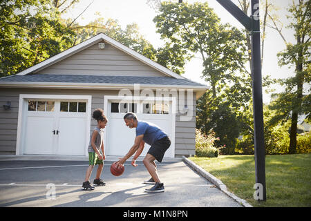 Vater und Sohn Basketball spielen in der Einfahrt zu Hause Stockfoto