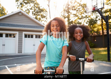 Bruder und Schwester, Motorroller in der Einfahrt zu Hause Stockfoto