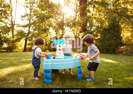 Gruppe Junger Kinder spielen mit Wasser im Garten Stockfoto