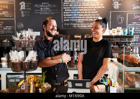 Männliche und weibliche Baristas hinter Zähler in Coffee Shop Stockfoto