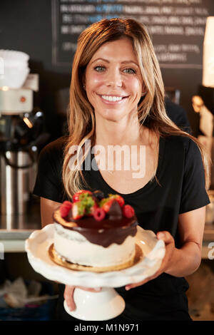 Kellnerin mit frisch gebackenem Kuchen mit Buttercream Frosting Stockfoto