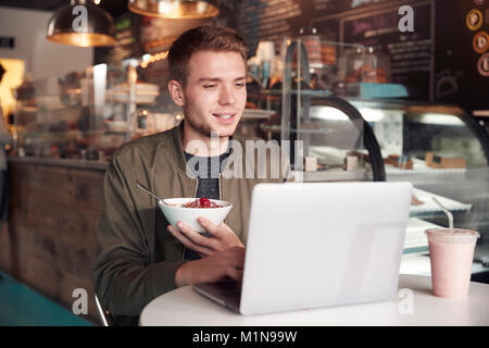Junger Mann mit Laptop im Cafe essen Frühstück Stockfoto