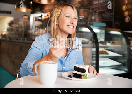 Frau im Café sitzen am Tisch essen Kuchen Stockfoto