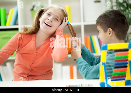 Boy's ziehen Mädchen Haare, flirten Stockfoto