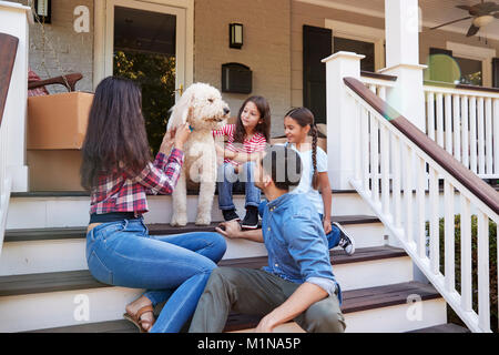 Familie mit Hund sitzen auf die Schritte der neuen Heimat unter Umzug in Tag Stockfoto