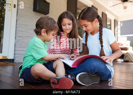 Gruppe der Kinder sitzen auf der Veranda des Hauses gemeinsam Bücher lesen Stockfoto