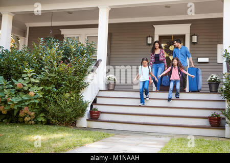 Familie mit Gepäck verlassen Haus für Ferienhäuser Stockfoto