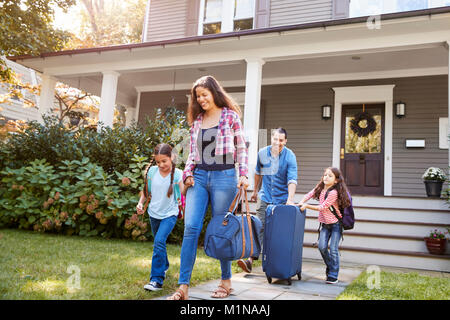 Familie mit Gepäck verlassen Haus für Ferienhäuser Stockfoto