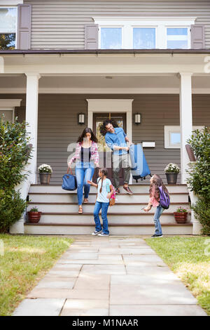 Familie mit Gepäck verlassen Haus für Ferienhäuser Stockfoto