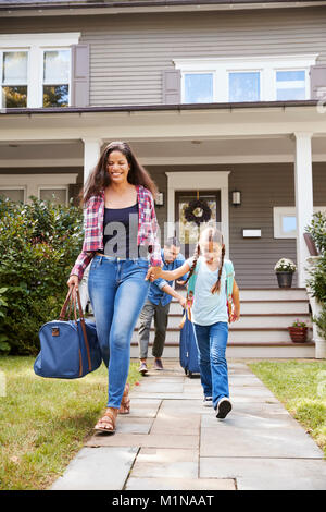 Familie mit Gepäck verlassen Haus für Ferienhäuser Stockfoto