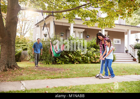 Kinder spielen auf den Garten schwingen und Scooter vor dem Haus Stockfoto