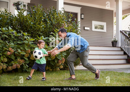 Vater Fußball spielen im Garten mit Sohn Stockfoto