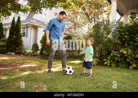 Vater Fußball spielen im Garten mit Sohn Stockfoto