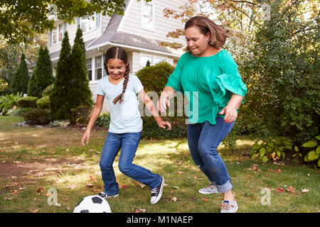 Großmutter Fußball spielen im Garten mit Enkeltochter Stockfoto