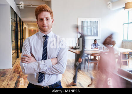 Porträt der jungen rothaarigen Mann, der in einer hektischen modernen Arbeitsplatz Stockfoto