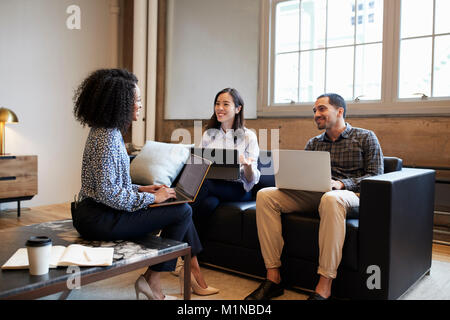 Lächelnd Arbeitskollegen mit Laptops bei der zufälligen Begegnung Stockfoto