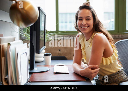 Weiße Frau an einem Computer in einem Büro Lächeln für die Kamera Stockfoto