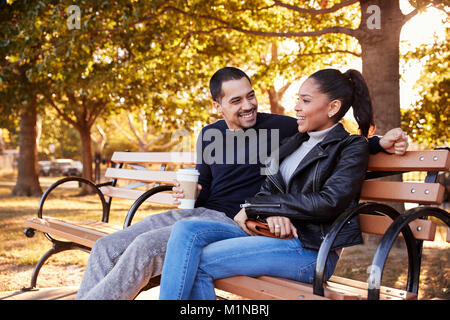 Junge Hispanic Paar sitzt auf der Bank in Brooklyn Park Stockfoto