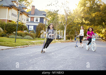 Drei vor - jugendlich Mädchen spielen in der Straße am Roller und Fahrrad Stockfoto