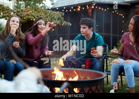 Teenage Freunde essen s'mores um eine Feuerstelle Stockfoto