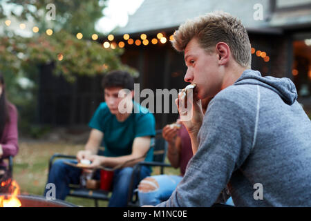 Teenager Essen s'More mit Freunden an einer Feuerstelle Stockfoto