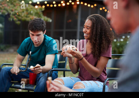 Schwarze Mädchen im Teenageralter, s'More mit Freunden an einer Feuerstelle Stockfoto