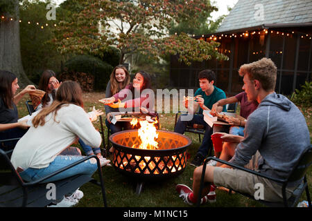 Teenage Freunde sitzen eine Feuerstelle essen Pizza zum Mitnehmen Stockfoto